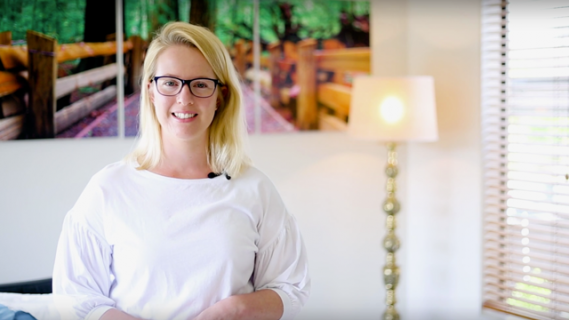 Woman standing in room with lamp and wall picture in background